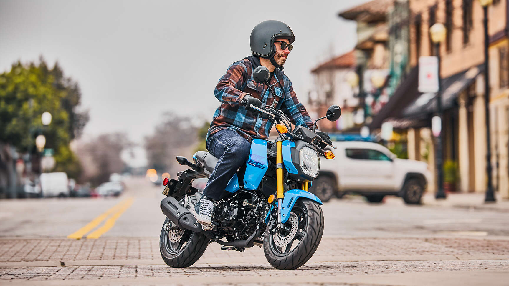 MSX125 Grom kék színben közúton halad, a motoros belép a kanyarba